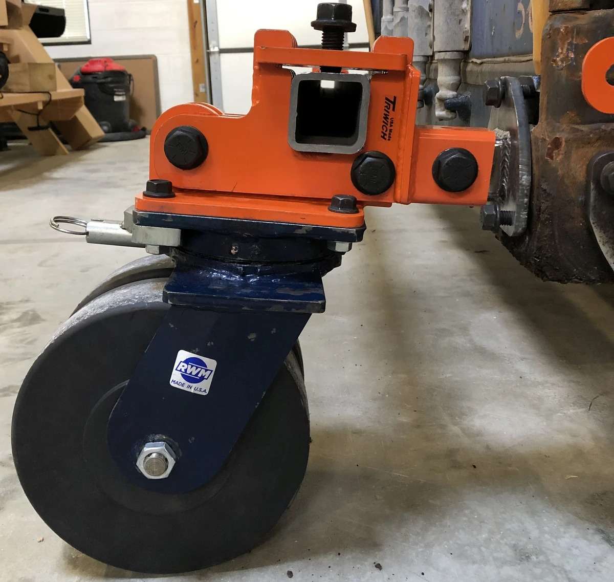 Industrial orange caster wheel on machinery.