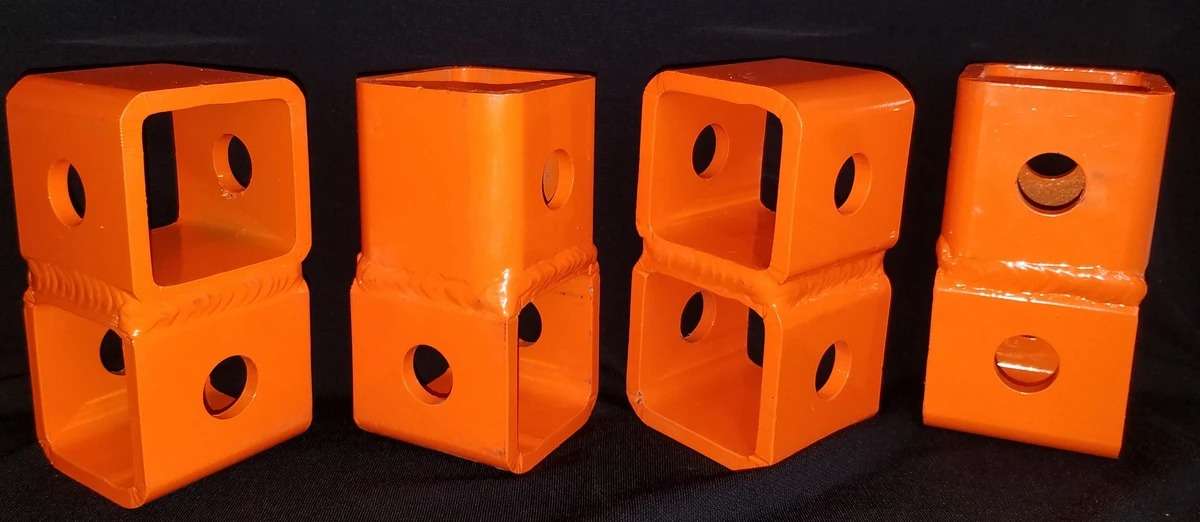 Four orange construction beam clamps.