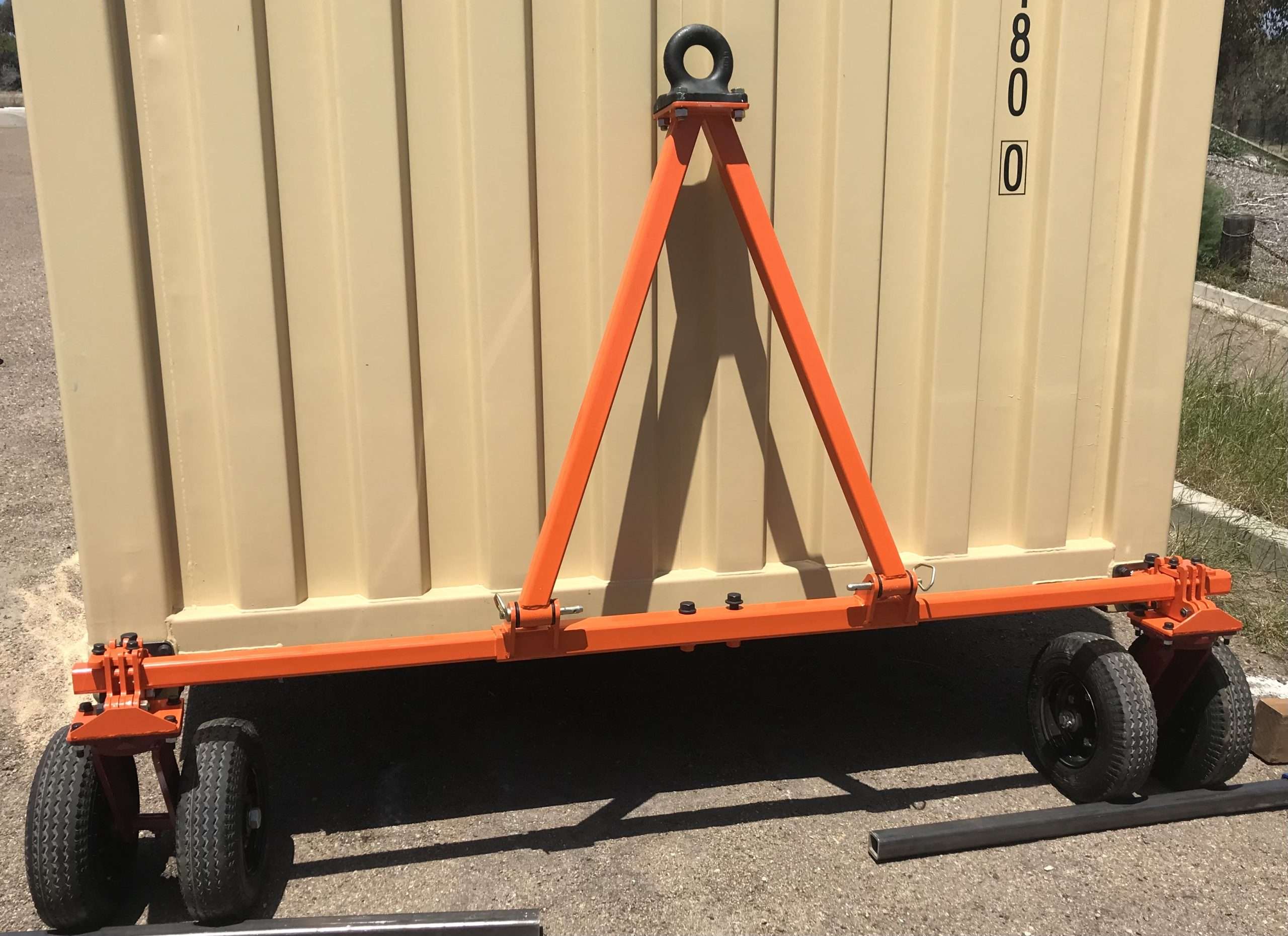 Orange container spreader with wheels outdoors.
